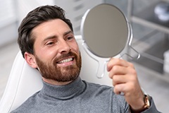 Man smiling in the mirror with new dental implants