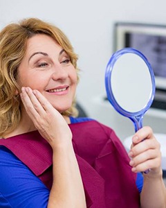 dental patient looking at her new smile in the mirror