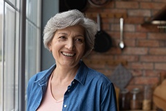 Woman smiling by a window with dental implants