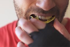 closeup of a man putting in a mouthguard for sports 