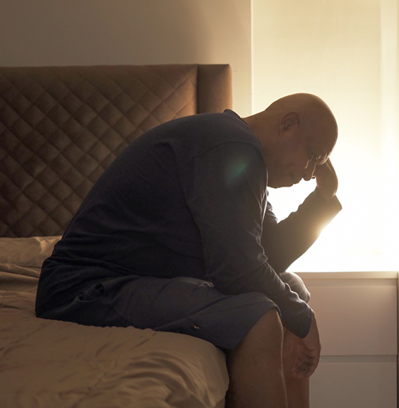 Tired man sitting on his bed