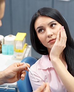 a patient holding their cheek and looking at their dentist