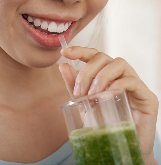 Person drinking a green beverage through a straw