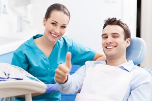 man in dentist chair giving thumbs up