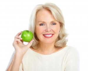 older woman smiling holding an apple