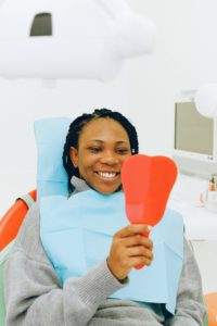 Smiling woman in dental chair holding mirror