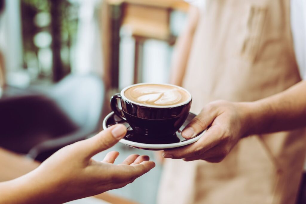 A waiter handing coffee to a customer
